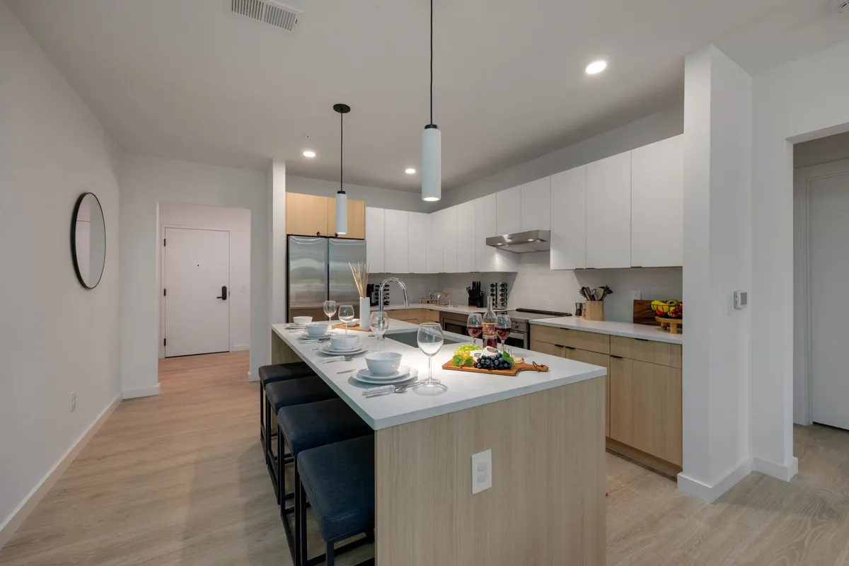 An inviting kitchen and dining area showcasing a kitchen island with bar stools, a formal dining setup, large refrigerator, and white cabinetry. The space exudes comfort and is clearly intended for both entertaining and everyday living.