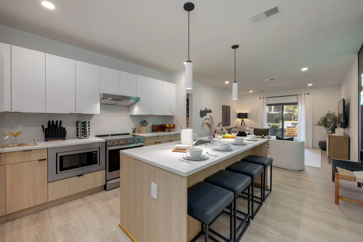 A modern kitchen with a central island, stainless steel appliances, a casual dining setup, and large windows. The space is bright, well-organized, and ideal for both cooking and entertaining.