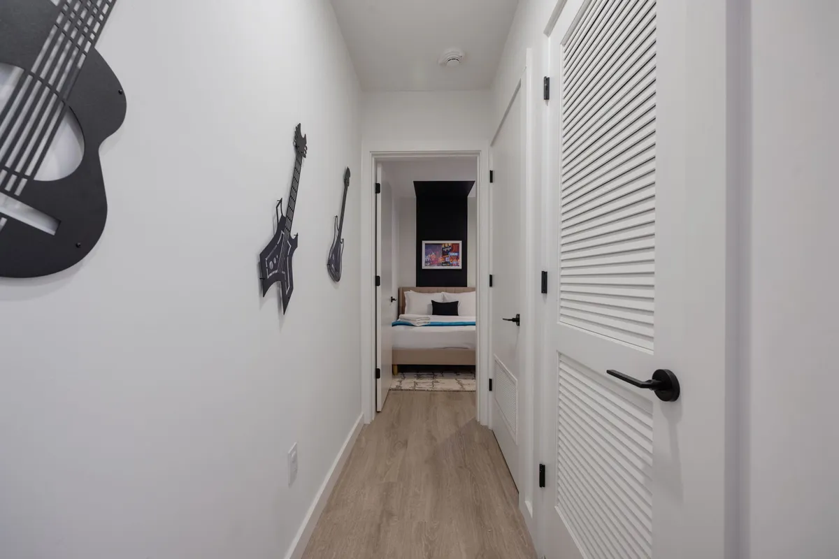 A creative, music-themed interior shot with guitar wall art and an open bedroom door. The setup feels welcoming, youthful, and unique, inviting guests to relax or socialize in a space that celebrates local culture.
