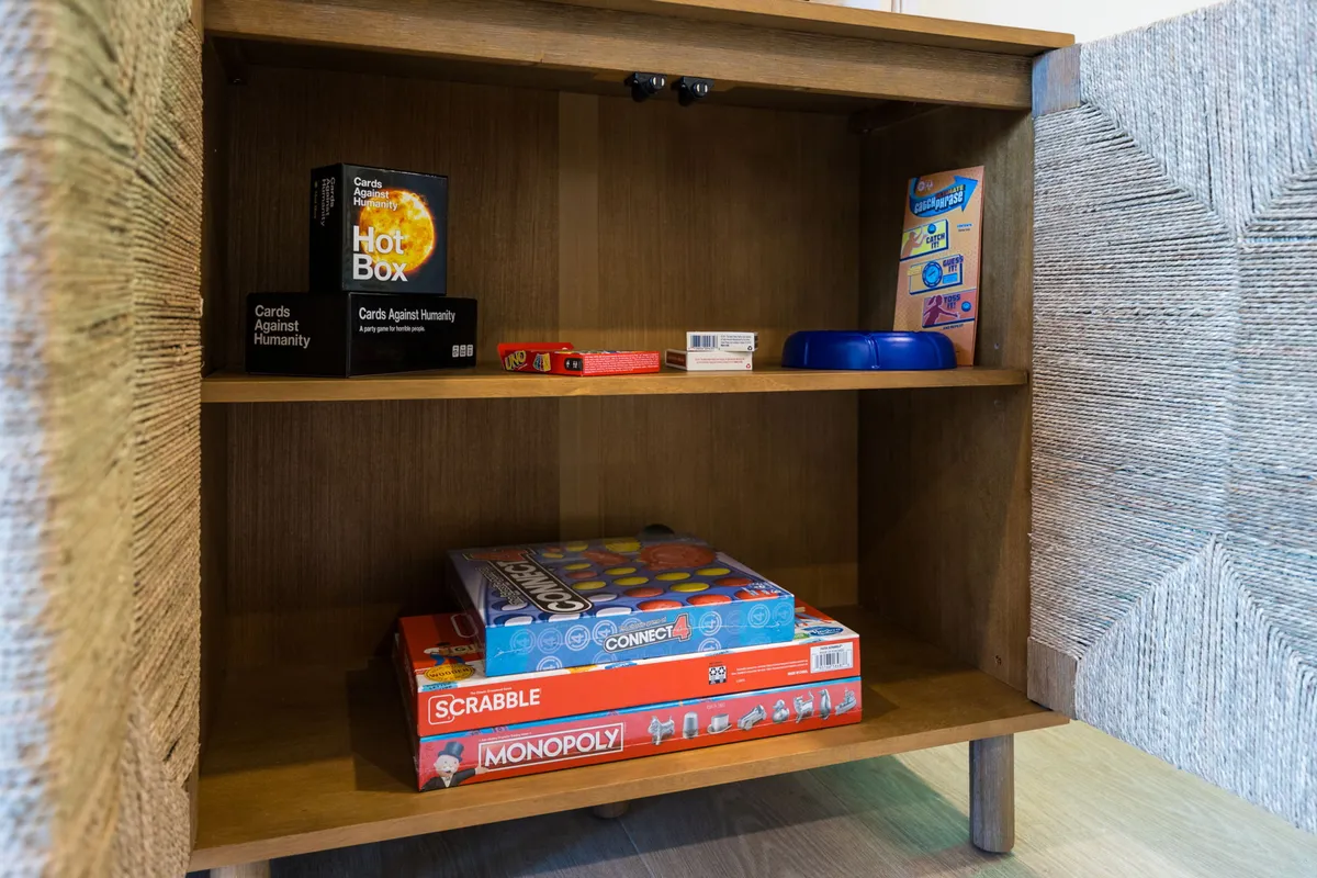 A playful nook featuring a collection of board games on open shelves and a wooden cabinet, radiating an atmosphere of fun and camaraderie.